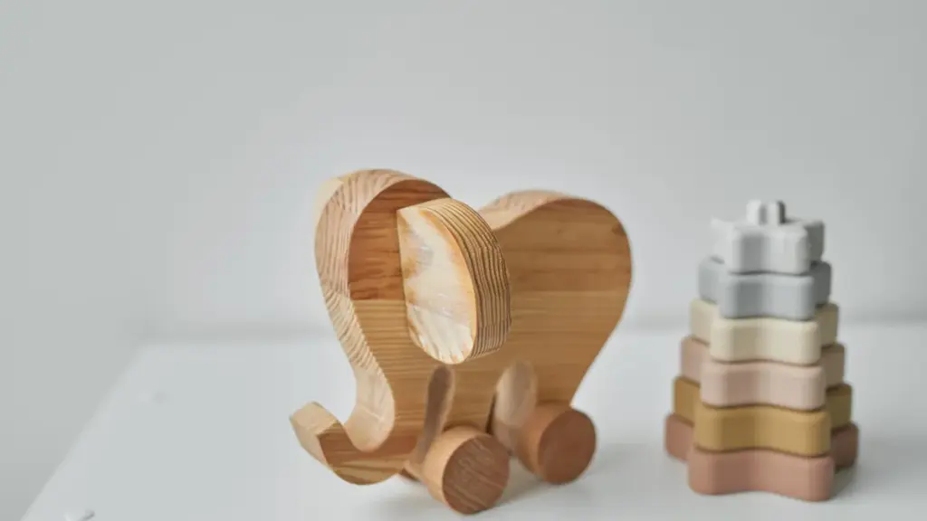 Brinquedo de madeira em forma de elefante ao lado de peças de empilhar.
