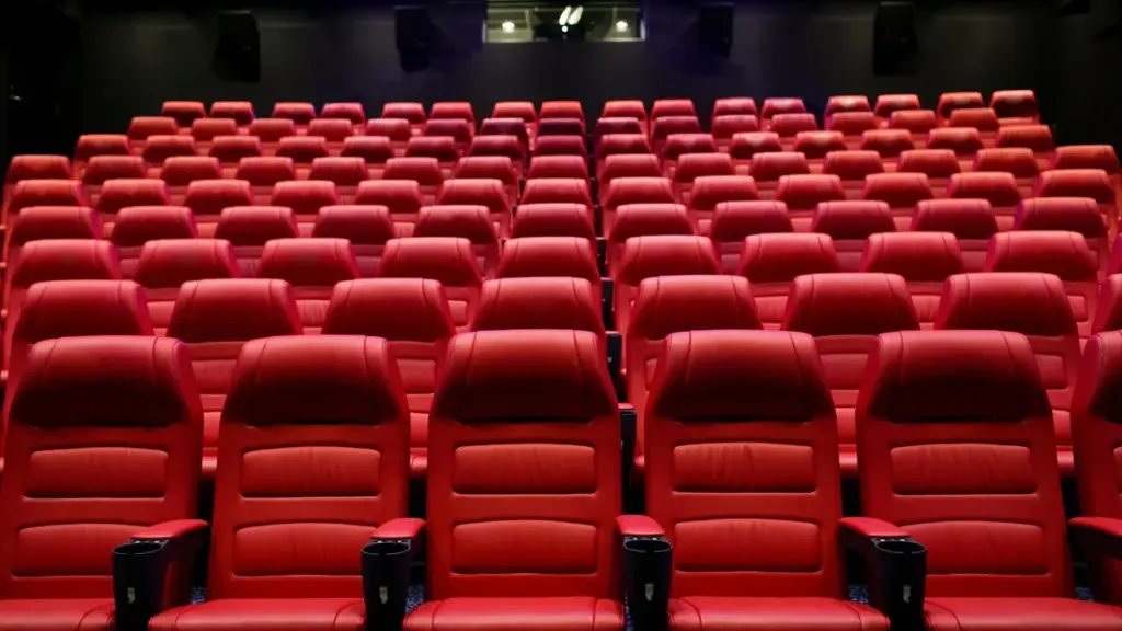 Fileiras de poltronas vermelhas em uma sala de cinema vazia