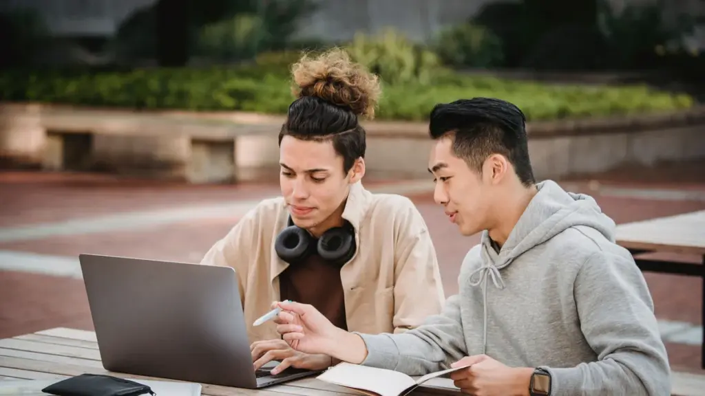 Duas pessoas estudando com notebook e caderno, imagem ilustrativa