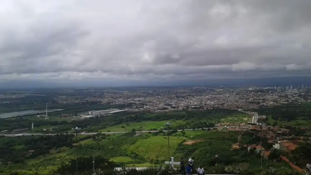 Vista urbana de Juazeiro do Norte a partir do Horto, com vegetação em primeiro plano e céu nublado